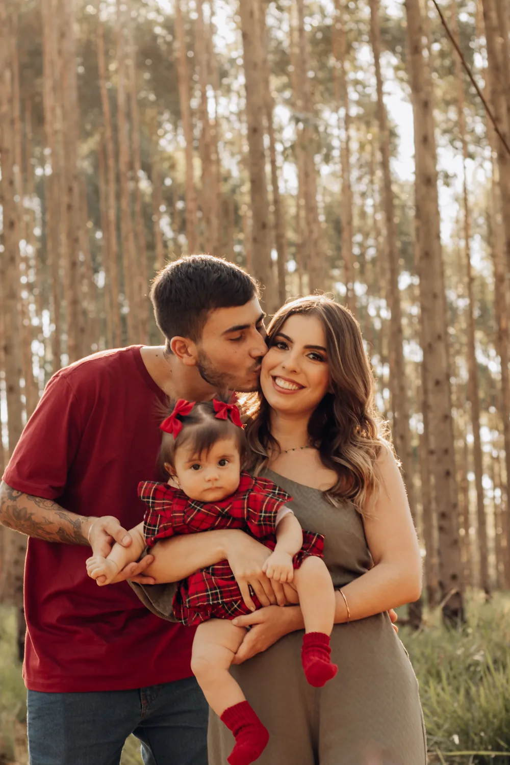 Casal com o bebê no colo num bosque